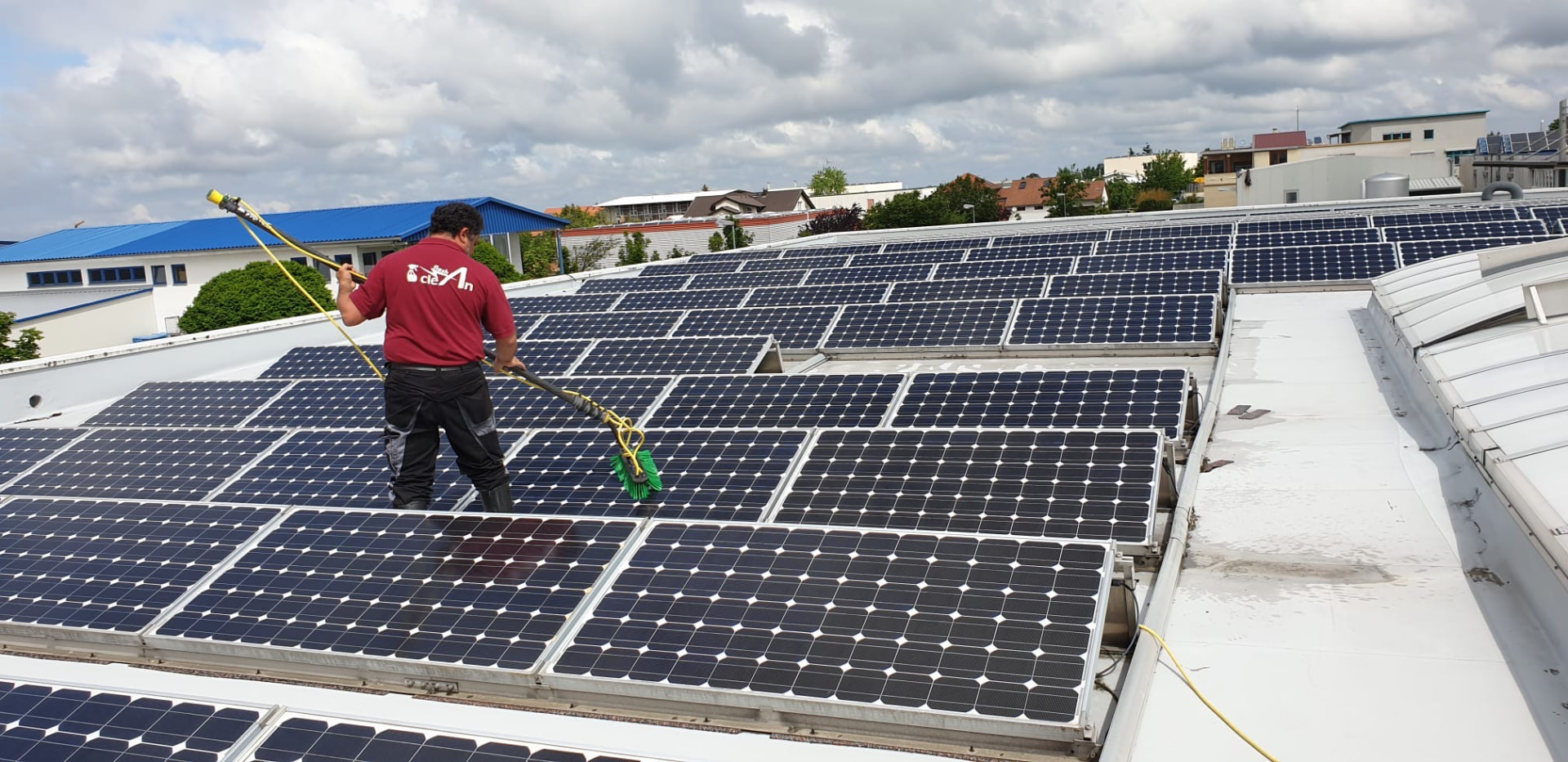Mitarbeiter reinigt Solarmodule auf einem Flachdach